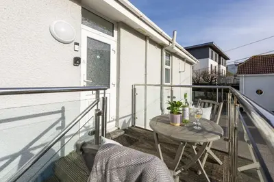 a balcony with a table and chairs on a building at Beachside Fistral, Newquay in Newquay