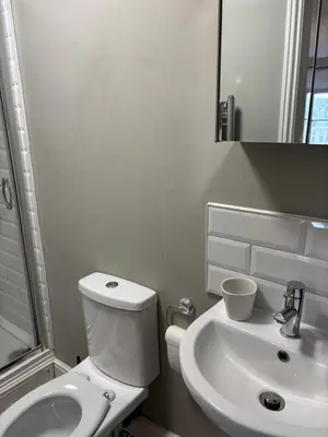 a white bathroom with a toilet and a sink at The Mariners in Falmouth