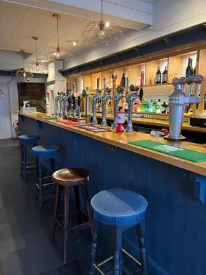 a bar with blue bar stools in a room at The Mariners in Falmouth