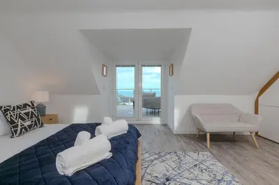 a bedroom with a bed and a chair at Solstice in Carbis Bay
