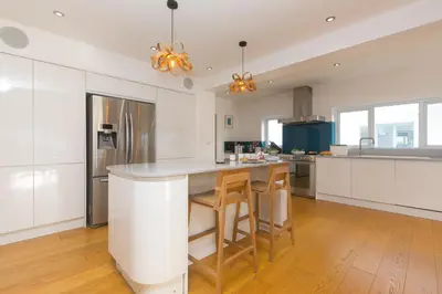 a kitchen with white cabinets and a kitchen island with stools at Solstice in Carbis Bay