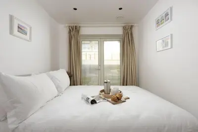 a white bed with a camera and a teddy bear on it at Close to the Beach, Wi-Fi, Parking in Newquay