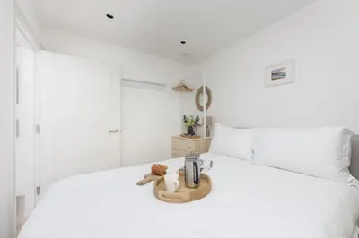 a white bedroom with a white bed with a wooden tray at Close to the Beach, Wi-Fi, Parking in Newquay