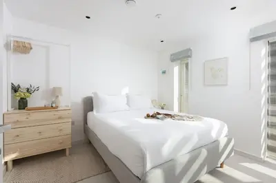 a white bedroom with a large bed and a dresser at Close to the Beach, Wi-Fi, Parking in Newquay