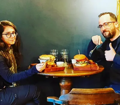 a man and a woman sitting at a table with sandwiches at Jacobs Ladder Inn & Brewery in Falmouth