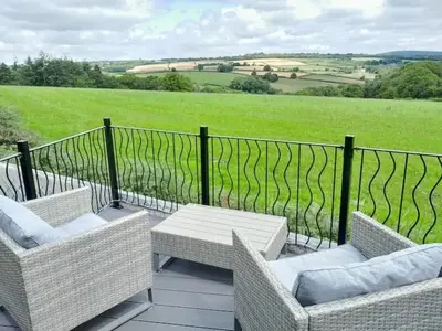 a balcony with wicker chairs and tables and a fence at Hillview Haven in Liskeard