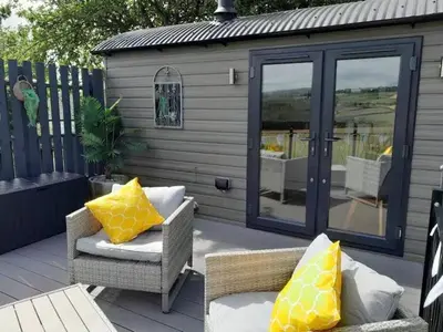 a patio with two chairs with yellow pillows on it at Hillview Haven in Liskeard
