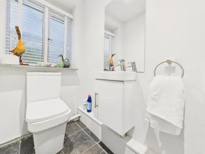 a white bathroom with a toilet and a sink at Cosy Cornish Cottage with Firepit & Parking in Newlyn East