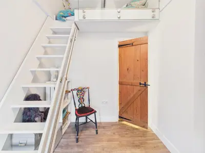 a room with stairs and a red chair at Cosy Cornish Cottage with Firepit & Parking in Newlyn East