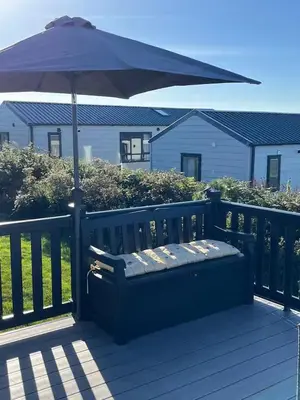 a blue bench with an umbrella on a deck at Stunning Lodge with sea and country views, sleeps 6 in Newquay