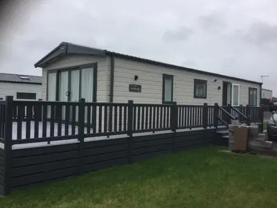 a mobile home with a fence and grass at Stunning Lodge with sea and country views, sleeps 6 in Newquay