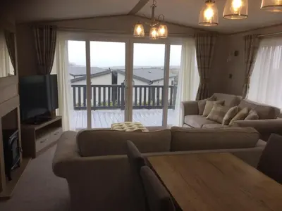 a living room with a couch and a table and a television at Stunning Lodge with sea and country views, sleeps 6 in Newquay