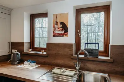 a kitchen with a sink and two windows at Heron's Perch- A pond-side retreat with cinema room in Callington