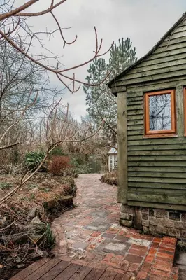 a house with a brick walkway next to a building at Heron's Perch- A pond-side retreat with cinema room in Callington