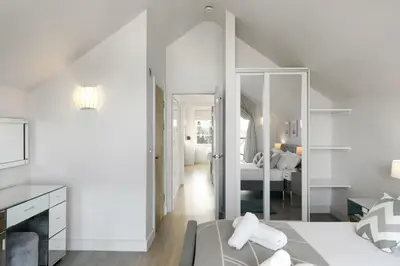 a white bedroom with a bed and a mirror at Bright & Modern Townhouse Private Parking in Newquay