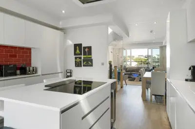 a kitchen with a white counter and a living room at Bright & Modern Townhouse Private Parking in Newquay
