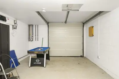 a garage with a ping pong table and a garage door at Bright & Modern Townhouse Private Parking in Newquay