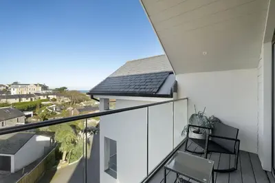 a balcony with two chairs and a view of the ocean at Bright & Modern Townhouse Private Parking in Newquay