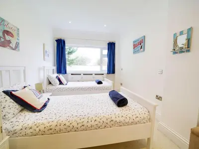 two beds in a bedroom with blue curtains at Port View House in Bodmin