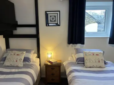 two twin beds in a room with a window at Malt-Barn Conversion, with access to Pool & Hot Tub-at Fox Valley Cottages in Lansallos