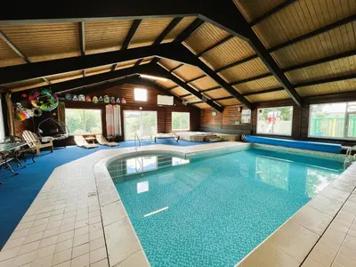 a large swimming pool in a large room with at Malt-Barn Conversion, with access to Pool & Hot Tub-at Fox Valley Cottages in Lansallos
