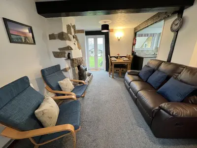 a living room with a leather couch and chairs at Malt-Barn Conversion, with access to Pool & Hot Tub-at Fox Valley Cottages in Lansallos
