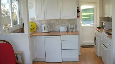 a kitchen with white cabinets and a counter top at Clonmore Beach Chalet, Riviere Towans in Hayle