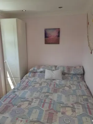a bedroom with a bed with a quilt on it at Clonmore Beach Chalet, Riviere Towans in Hayle