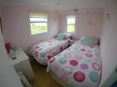 a bedroom with two beds and a window at Clonmore Beach Chalet, Riviere Towans in Hayle