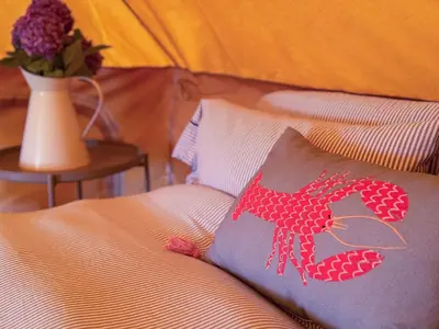 a bed with a pillow with a red lobster on it at Furnished Bell Tent 4 in St Austell
