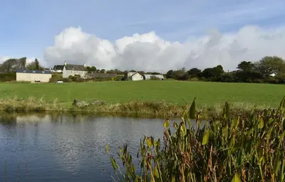a body of water with a field and houses in the background at Seaview Stable Barn in Penryn