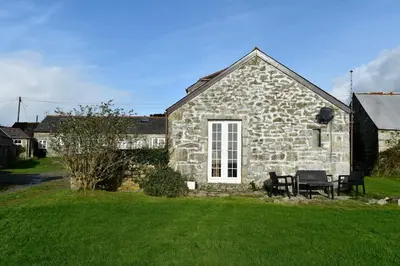 a stone house with two benches in front of it at Seaview Stable Barn in Penryn