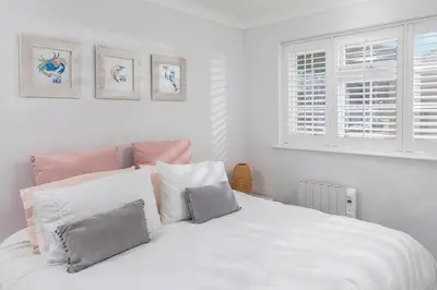 a white bedroom with a large white bed with pillows at Sandy Nook, Portreath, Cornwall in Portreath
