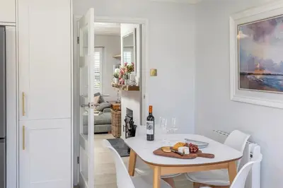 a white dining room with a white table and chairs at Sandy Nook, Portreath, Cornwall in Portreath