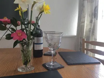 a table with a bottle of wine and a vase of flowers at flat with Cornish charm, parking and garden in St Ives