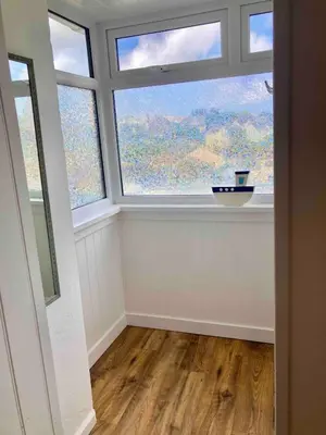 an empty room with a large window and wooden floors at flat with Cornish charm, parking and garden in St Ives