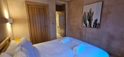 a bedroom with a white bed in front of a door at Shorebreak Apartment 1 in Newquay