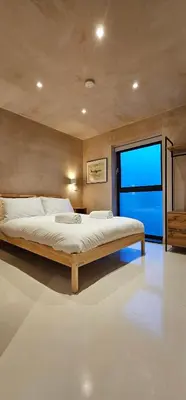 a bedroom with a large bed and a large window at Shorebreak Apartment 1 in Newquay