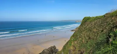 a beach with people on the sand and the ocean at Shorebreak Apartment 1 in Newquay