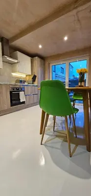 a green chair in a kitchen with a table at Shorebreak Apartment 1 in Newquay