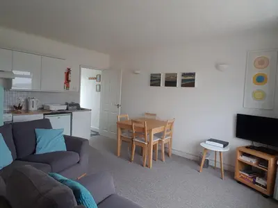a living room with a couch and a table and a kitchen at Seaview Apartment in Phillack