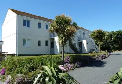 a large white house with palm trees in front of it at Seaview Apartment in Phillack