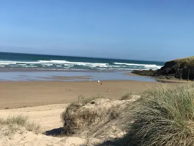 a beach with people walking on the sand and the ocean at Little Dusty - Between St Agnes & Perranporth in St. Agnes
