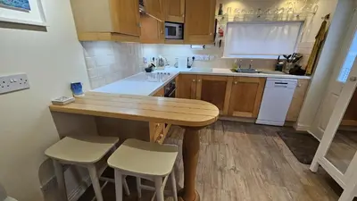 a kitchen with a wooden table and white appliances at Potted Shrimp in Saint Mawes