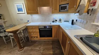 a kitchen with wooden cabinets and a counter top at Potted Shrimp in Saint Mawes