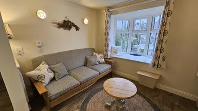 a living room with a couch and a window at Potted Shrimp in Saint Mawes
