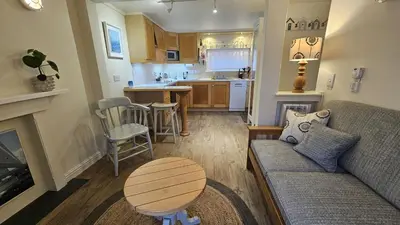 a living room with a couch and a table and a kitchen at Potted Shrimp in Saint Mawes