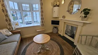 a living room with a table and a fireplace at Potted Shrimp in Saint Mawes