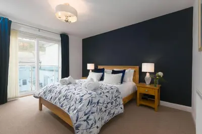 a bedroom with a bed and a large window at Cockleshells in St Ives
