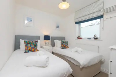 two twin beds in a room with white walls at Cockleshells in St Ives